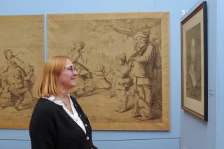 Eine Besucherin schaut auf ein Portrait in einer Ausstellung.