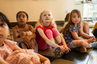Kinder sitzen im Kreis und hören gespannt zu.