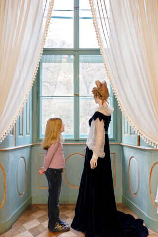Ein Mädchen betrachtet die Puppe von Prinzessin Adelheid im Schloss Elisabethenburg.