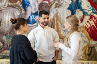 Zwei Frauen und ein Mann unterhalten sich in einem historischen Zimmer des Schlosses Elisabethenburg.