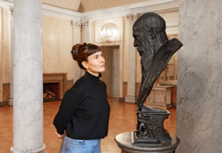 Eine Besucherin betrachtet die Georgs Büste im Marmorsaal des Schlosses Elisabethenburg.