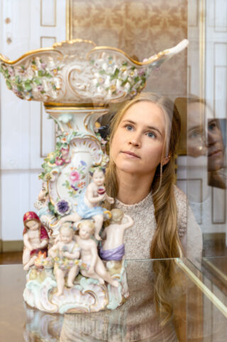 Eine Besucherin betrachtet einen Porzellan‑Tafelaufsatz im Schloss Elisabethenburg.